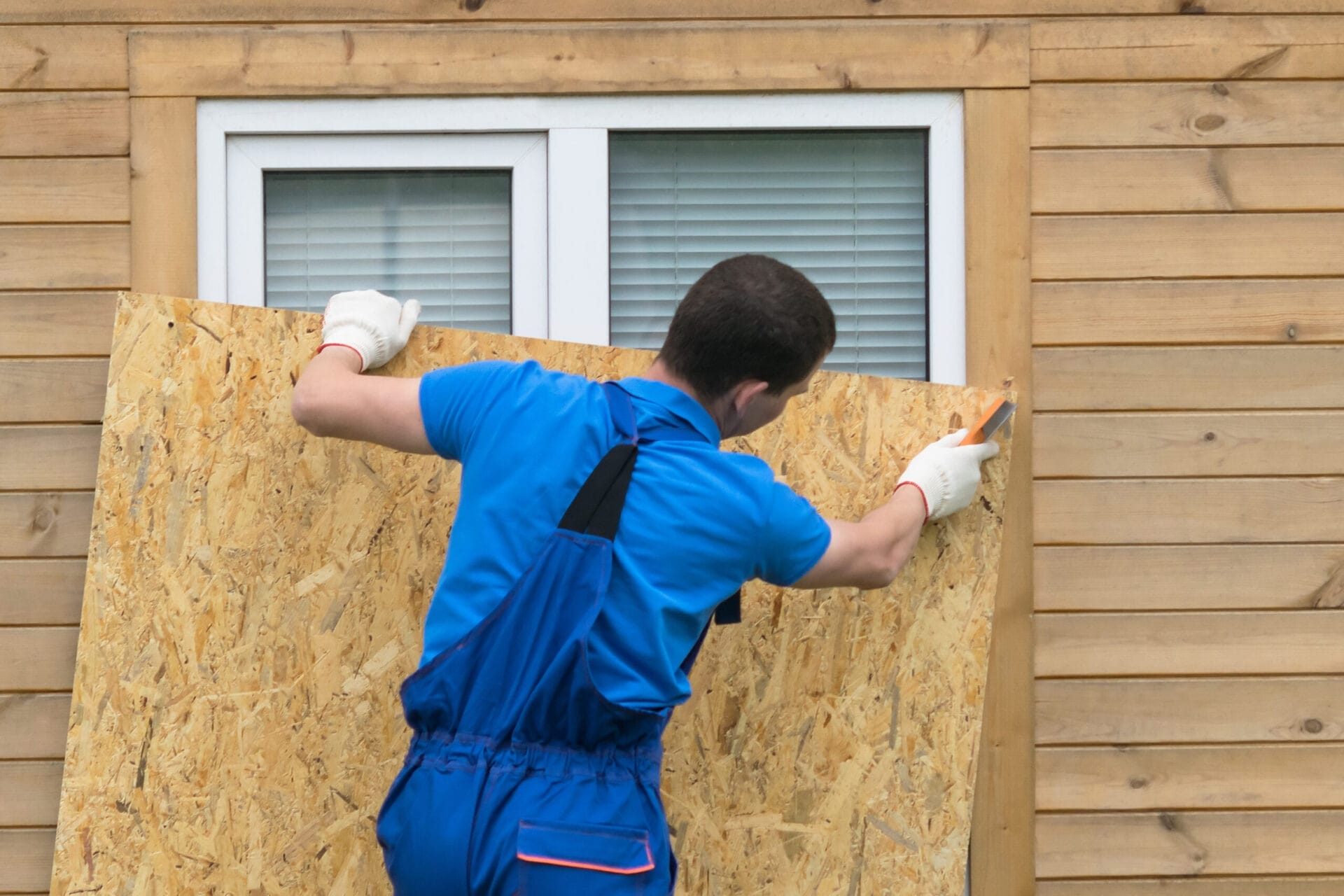 Restoration workers boarding up windows and securing a storm-damaged US home
